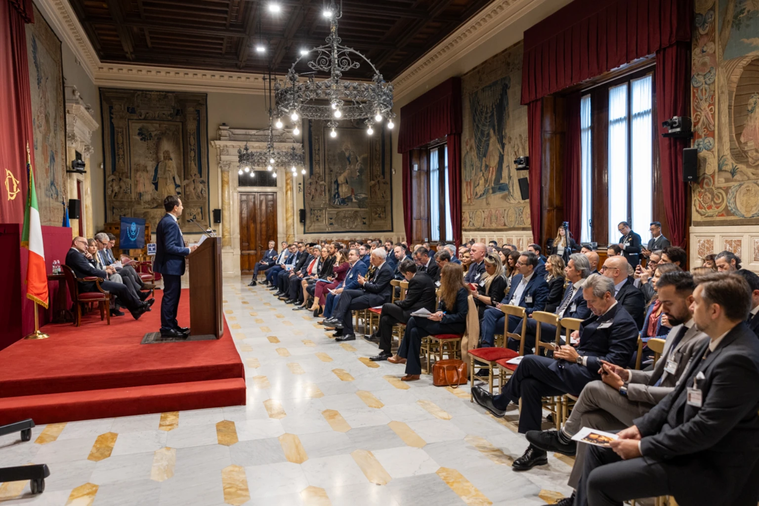 Un relatore si rivolge ai partecipanti dello Human Economic Forum in una sala del Parlamento italiano.